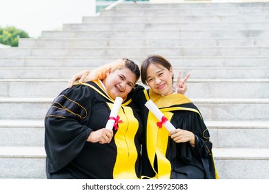 Happy Asian Graduate Student Holding The Diplomas On Hand During The University Graduation Ceremony. Master Degree Student In Gown Suit Holding A Diplomas For Photography.