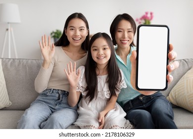 Happy Asian Grandmother, Mother And Daughter Waving Hi And Showing Big Blank Smartphone While Sitting Together On Couch At Home, Multi-generation Family Recommending New Mobile App, Collage, Mockup