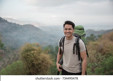 Happy Asian Hiker. Man With Backpack Hiking In Beautiful Forest