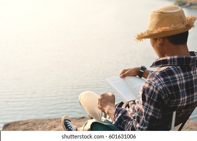 Happy Asian Hipster Man Reading A Book In Nature Background, Relax Time On Holiday Concept Travel , Color Of Vintage Tone And Soft Focus