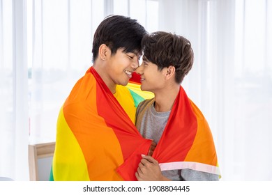 Happy Asian Homosexual Gay Couple Standing And Hugging Covering By Rainbow Pride Flag, LGBT Concept.