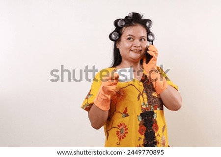 Happy asian housekeeper woman talking on the phone while looking above