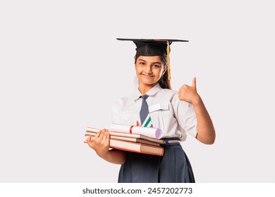 Happy Asian Indian schoolgirl wears school uniform and graduation cap against white background - Powered by Shutterstock