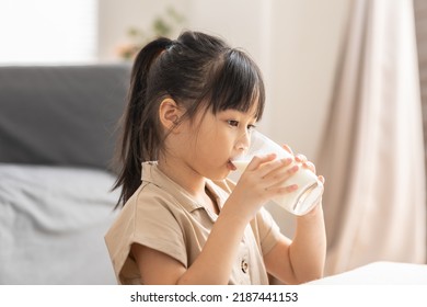 Happy Asian Kid Drinking Fresh Milk For Good Health At Home.Enjoy And Tasty For Strong Bone.Female Kid Drink Soy Milk From Glass Tasty And Delicious With Calcium.Healthy Lifestyle Concept