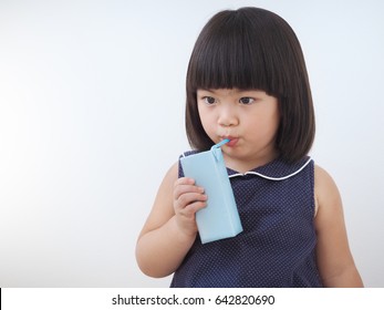 Happy Asian Kid Girl Drinking Milk From Carton Box With Straw, Blank Juice Package In Hand Of Healthy Child