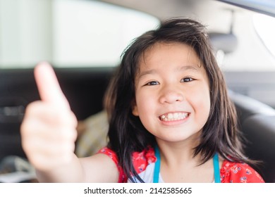 Happy Asian Kid Tween Girl Thumb Up With Smile On Seat.Family Riding Car Traveling By Automobile. Asian Family Parenting And Children Enjoying Summer Road Trip Together.Sibling Kids On Car Fun Trip.