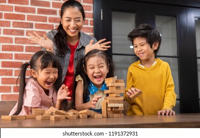 Happy Asian Kids And Their Teacher Are Playing Wooden Blocks Stack Game In Classroom At The School Together. Falling. Laughing.