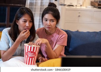 Happy Asian Lesbain Couple Watching Scary Movie On Television Together And Eating Popcorn At Sofa In Night Time At Home With Chill Ing Emotion.woman Friendship Lifestyle