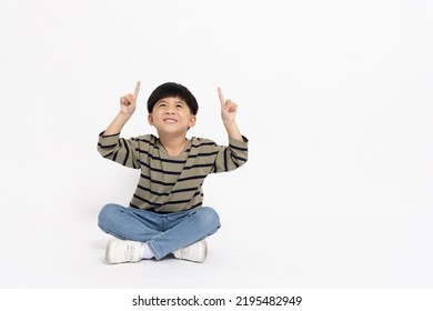 Happy Asian little boy pointing up with empty copy space and sitting on floor isolated on white background, Full body composition and five years old - Powered by Shutterstock