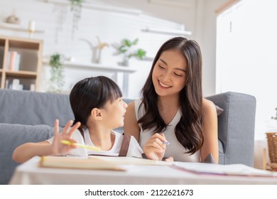 Happy Asian little girl doing homework with mother at home. Asian young mother teaching small daughter to drawing reading and writing to develop her daughter skill. Home School Concept - Powered by Shutterstock