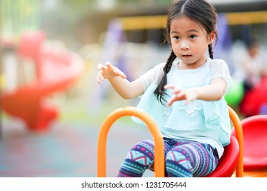 Happy Asian Little Girl Playing On Teetering Board In Playground. Kid Play See Saw        