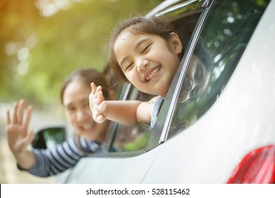 Happy Asian little girl playing on window car with mother, Family traveling on countryside