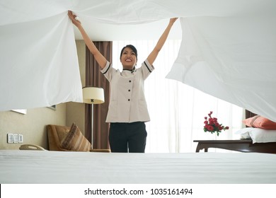 Happy Asian Maid Changing Bedding In Hotel Room