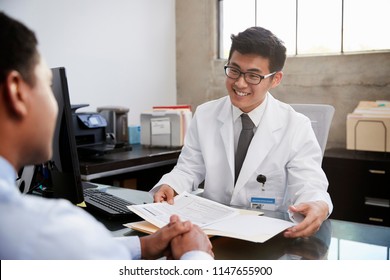 Happy Asian Male Doctor In Consultation With Male Patient