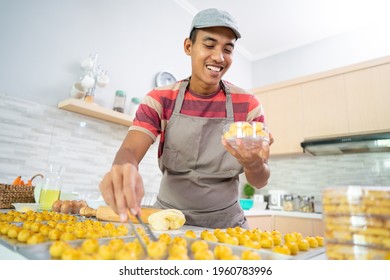 happy asian male homemade cake. portrait of young man put nastar cake on a plastic container box