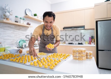 happy asian male homemade cake. portrait of young man put nastar cake on a plastic container box