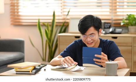 Happy asian man calculating money bank loan and managing expenses finances in living room. Household finance concept - Shutterstock ID 2205809775