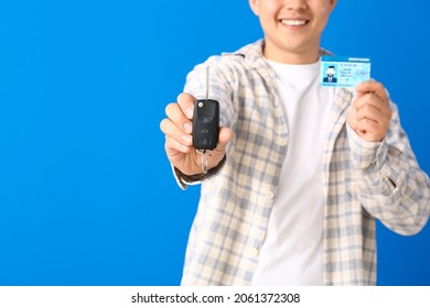 Happy Asian man with car key and driving license on color background