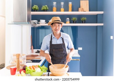 Happy Asian Man Cooking Healthy Food. Handsome Gentleman Making Salad For Breakfast And Dinner With Fresh Ingredients. Fun Cheerful Male Home Cook Preparing Delightful Vegetable For Delicious Salad.