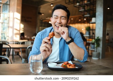 Happy  Asian Man Eating BBQ Chicken Wings In Restaurant.