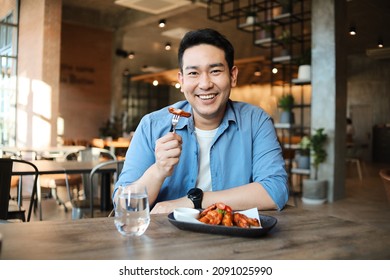 Happy  Asian Man Eating BBQ Chicken Wings In Restaurant.