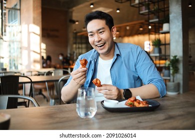 Happy  Asian Man Eating BBQ Chicken Wings In Restaurant.