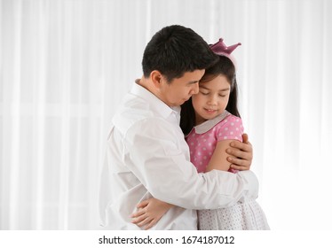 Happy Asian man and his little daughter hugging at home - Shutterstock ID 1674187012