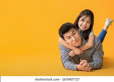 Happy Asian Man And His Little Daughter On Color Background