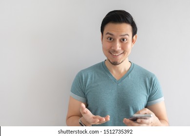 Happy Asian Man Is Showing A Great Mobile Application On Grey Background.