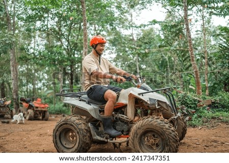 happy asian man smiling while riding the atv at atv arena inside the amusement park