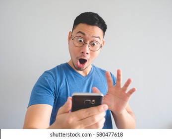 Happy Asian Man Using Smarphone With Shocked  And Surprised Face Expression.