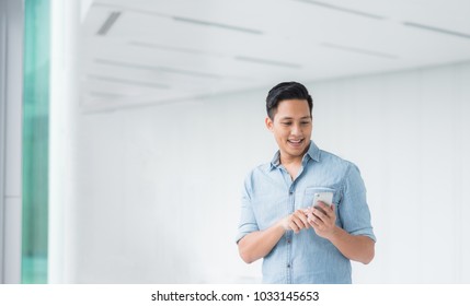 Happy Asian Man Using Smartphone Mobile In Modern Building 