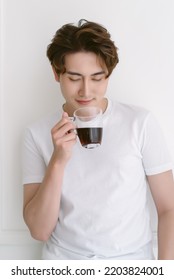 Happy Asian Man Wearing Casual Clothes Drinking Hot Coffee Standing Isolated On White Background. Peaceful Millennial Korean Guy Relaxing Day, Chilling On Lazy Morning Enjoy In Smell Of Fresh Coffee.