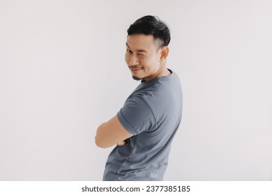 Happy asian man wears blue t-shirt and jeans winking at camera and smile.