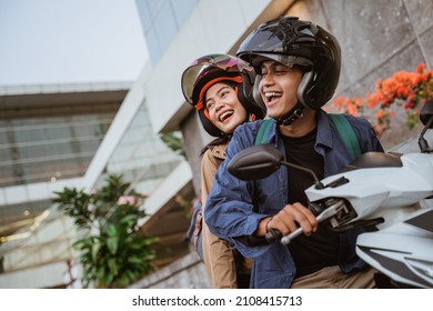 happy asian man and woman riding a motorcycle