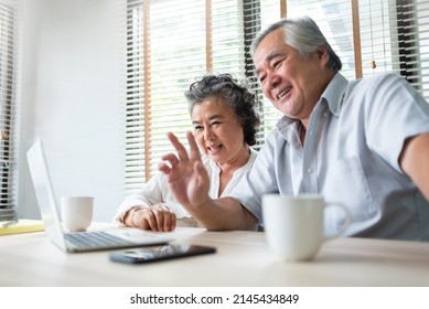 Happy Asian Mature Adult Couple Making Online Video Call And Waving Hands With Their Family On Laptop Computer.