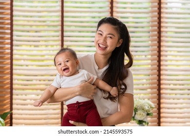 Happy Asian Mom Playing And Spending Time With Her Newborn Baby And Looking At Camera Together At Home.Adorable Baby Boy Smile Laughing With Mother In Warmth Place Relax And Comfortable.good Moment