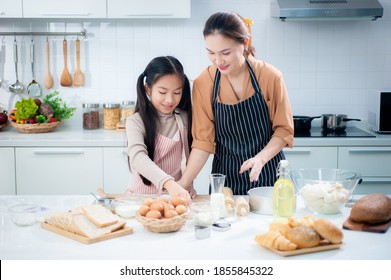 Happy Asian mother and adorable daughter helping knead the dough to make a bakery in the kitchen.It is a hobby and enhances professional or small business skills. - Powered by Shutterstock