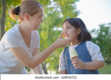 Happy Asian Mother Clean Her Daughter's Face While Eating With Soft Ice Cream Together