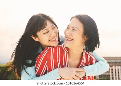 Happy Asian mother and daughter having fun outdoor - Chinese family people spending time together outside - Love, relationship and parenthood lifestyle concept