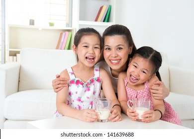 Happy Asian Mother And Daughters Drinking Milk At Home. Parent And Children. Beautiful Family Model.