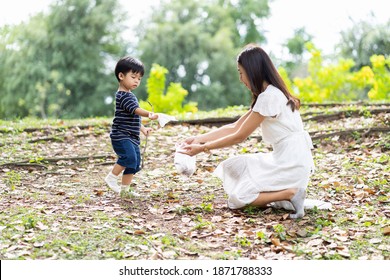 Happy Asian mother and little son are collecting trash into a bag. Mom and little boy volunteer charity environment outdoor in the park - Powered by Shutterstock