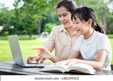 Happy asian mother,daughter enjoying using laptop computer in outdoor park,female tutor or teacher working,teaching child girl how to learning,student is interested in studying having fun,(education)  - Powered by Shutterstock