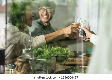 Happy Asian Multigenerational Family Of Dad Mom Daughter Girl And Grandfather Cheers Together During Lunch Meal Together With Joyful. Happy Family Engagement Togetherness Concept. Taken Outside Window