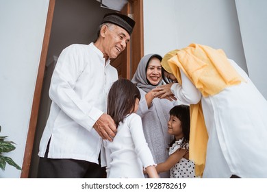 Happy asian muslim aged couple meeting kids and grand children at doorstep during eid mubarak celebration - Shutterstock ID 1928782619