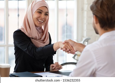 Happy Asian Muslim Businesswoman Hr Manager Employer Wear Hijab Handshake Hire Male Applicant Make Contract Deal With Partner Collaborate Shake Client Hand At Job Interview Business Meeting Concept