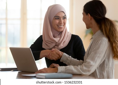Happy asian muslim businesswoman sales manager shake hand of caucasian lady client make deal with female customer at meeting with laptop, diverse women partnership, respect and collaboration concept - Shutterstock ID 1536232331