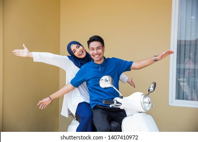 Happy Asian Muslim Couple Riding Motorcyle Or Scooter