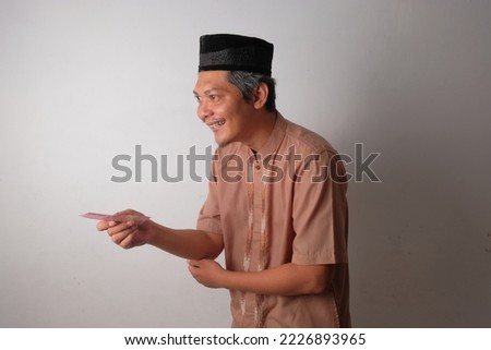 happy asian muslim man giving indonesian money for alms