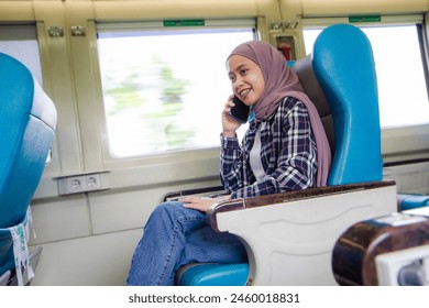 happy asian muslim woman talking on mobile phone while sitting in train wagon. traveling concept - Powered by Shutterstock